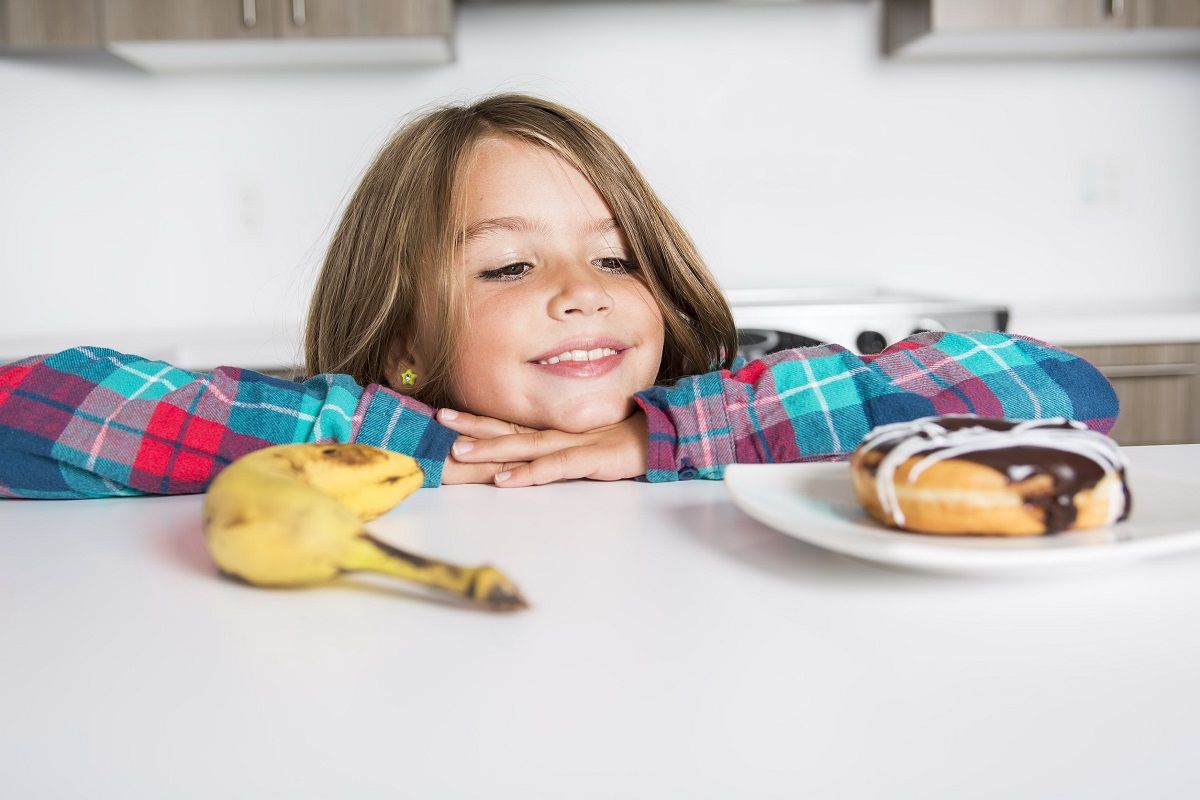 86443251 – a kid choosing between healthy vegetables and tasty sweets