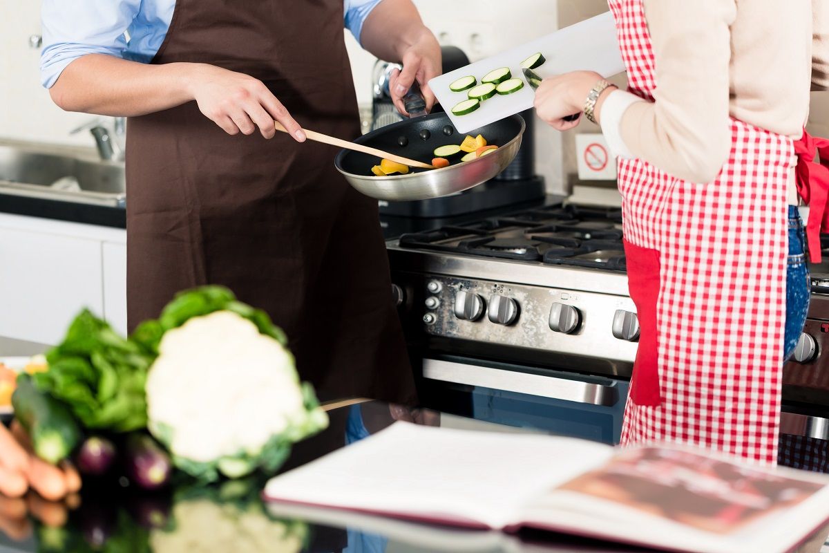 Asian couple cooking vegetables in frying pan