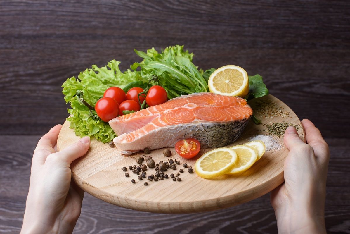 Woman holding a wooden plank with raw salmon