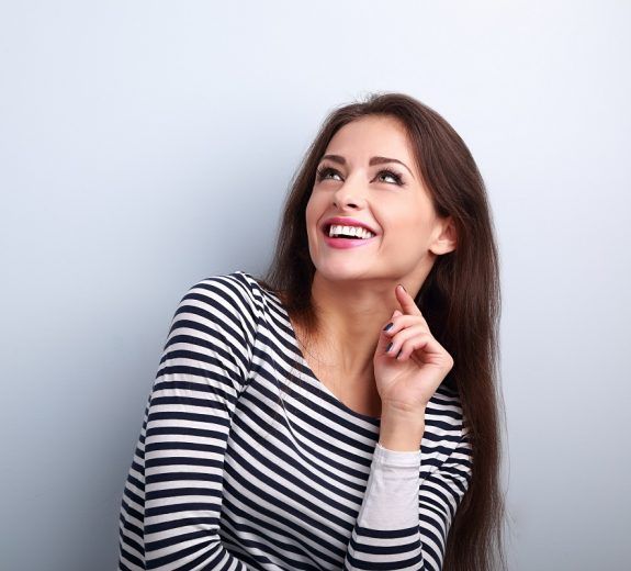 Happy emotional woman thinking and looking up with toothy smilin