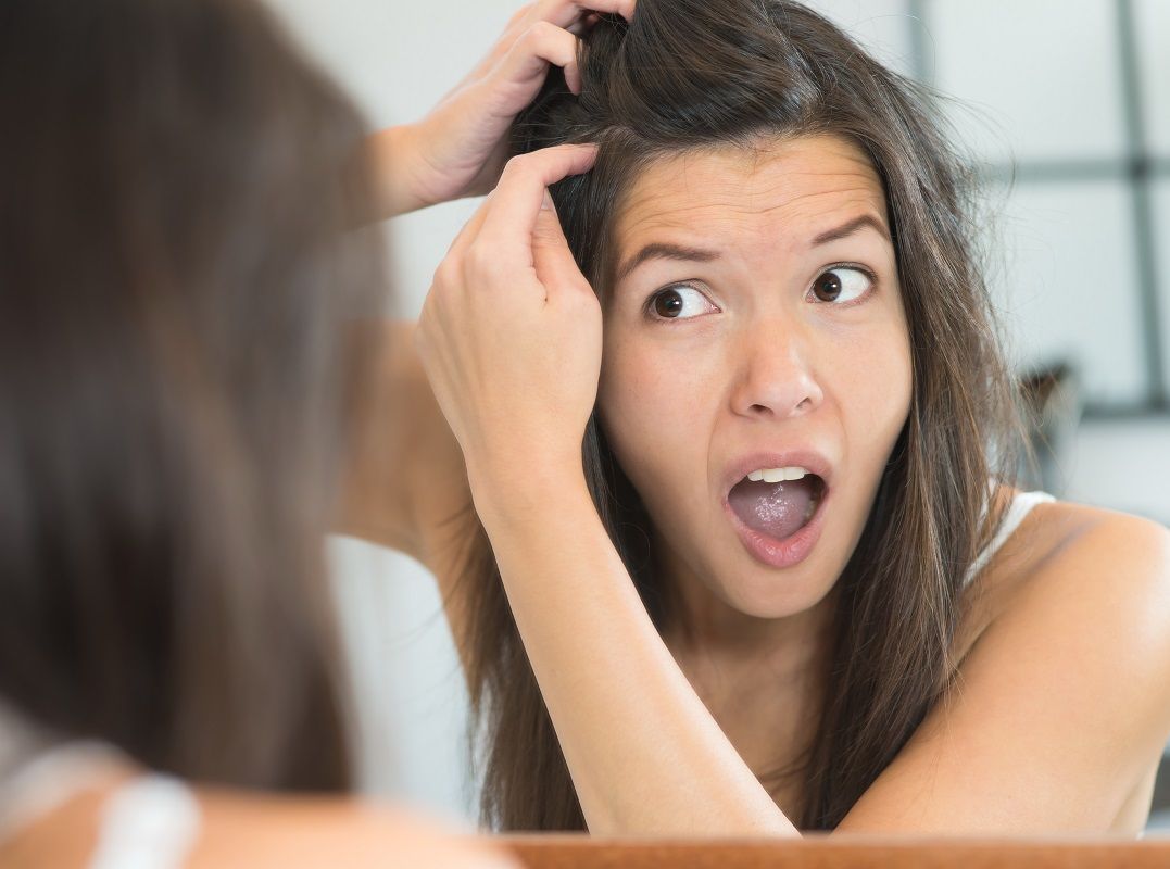 Horrified young woman looking in the mirror