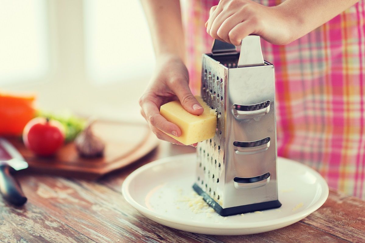 close up of female hands grating cheese