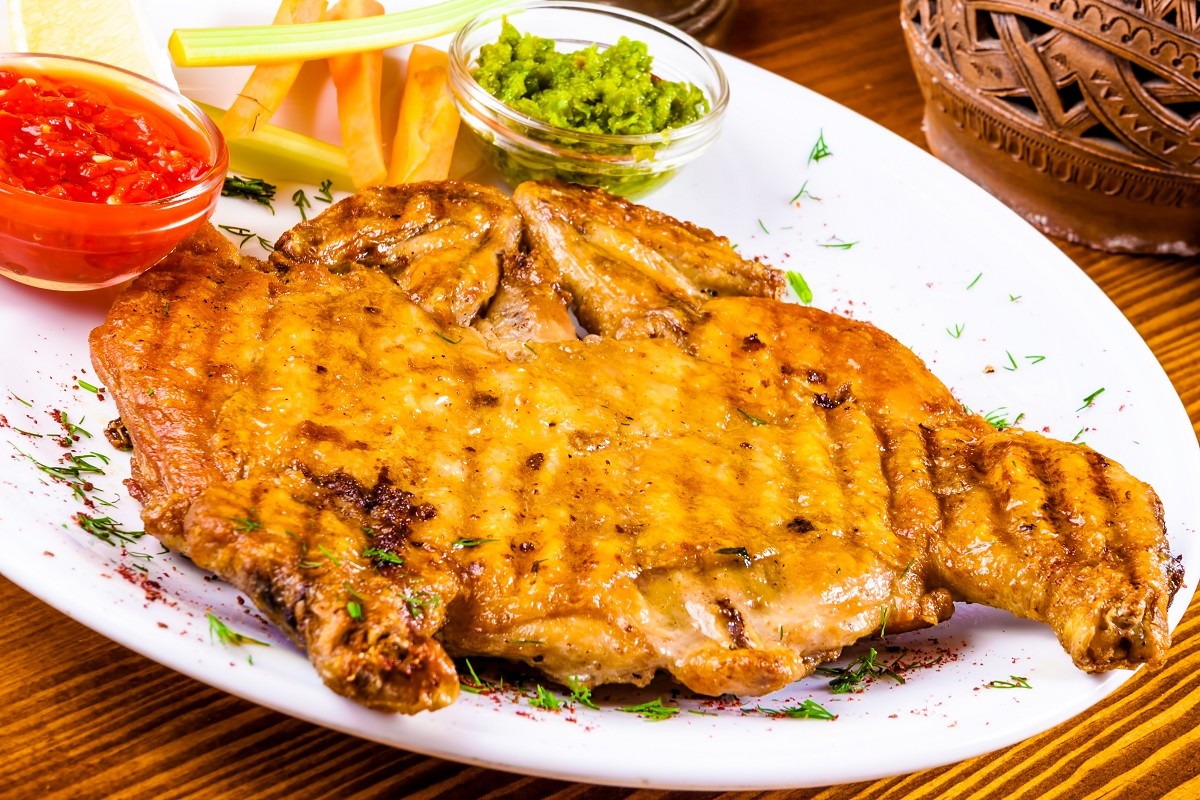 Grilled chicken tabaka or tapaka on white plate. Georgian cuisine