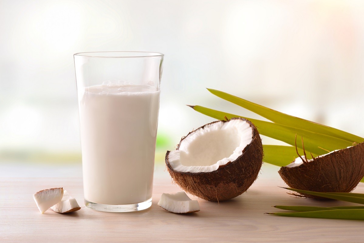 Coconut milk in glass with fruit on table in kitchen
