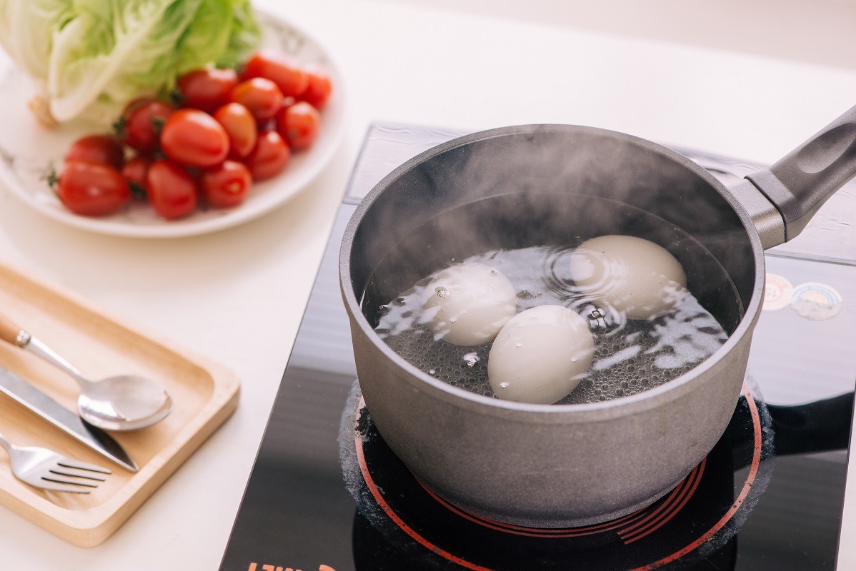 Three eggs boiling in pan of water