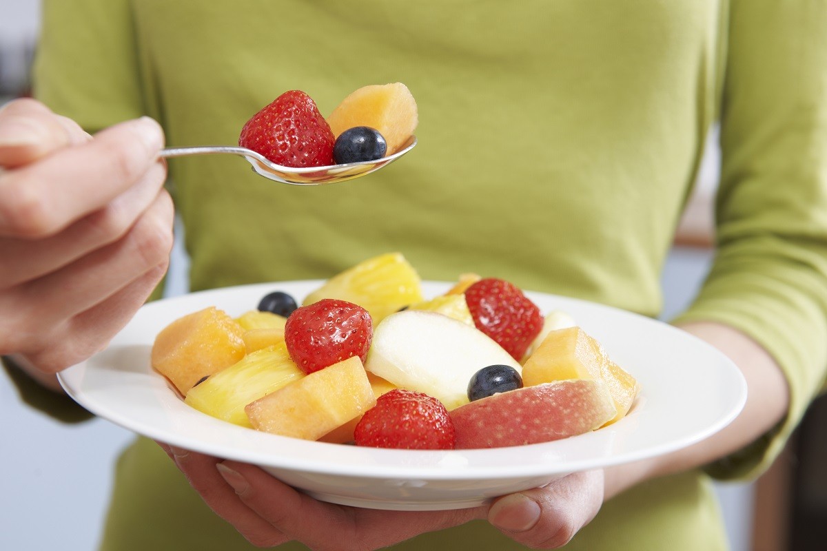 Close Up Of Woman Eating Bowl Of Fresh Fruit