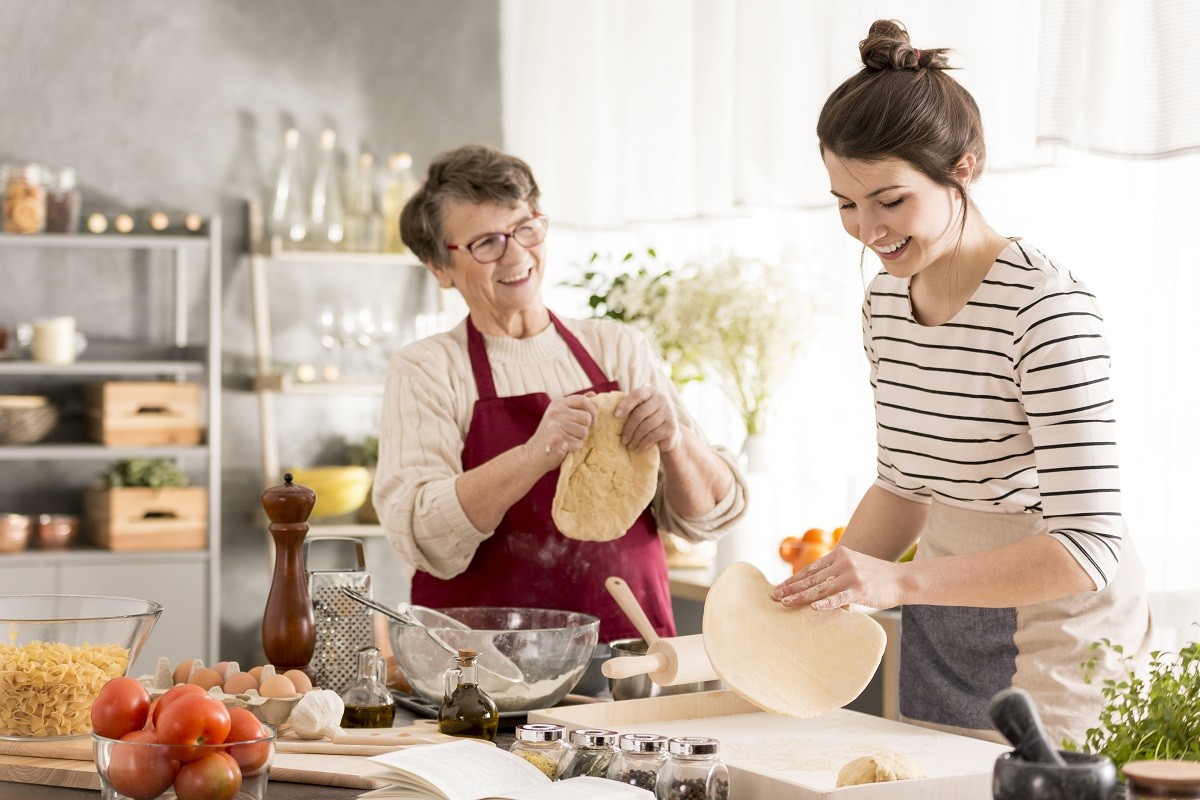 Grandmother preparing pizza with granddaughter