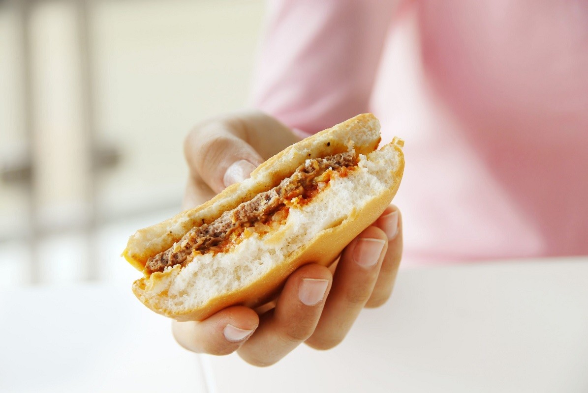 4754424 – half eaten hamburger in teen girl hand closeup