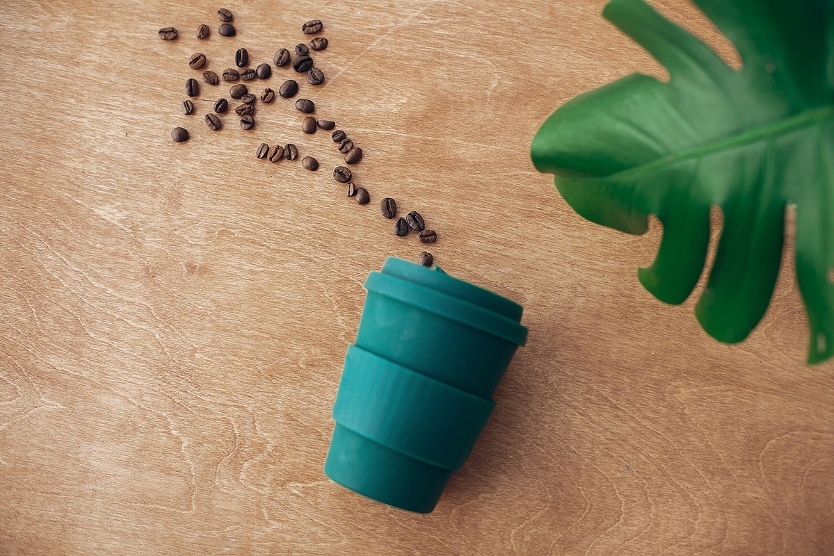 Stylish reusable eco coffee cup  on wooden background with roast