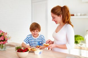 happy mother and son preparing snacks in the morning at home kitchen