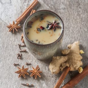 Traditional Indian masala tea in ceramic cup with spices to milk