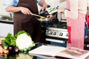 Asian couple cooking vegetables in frying pan