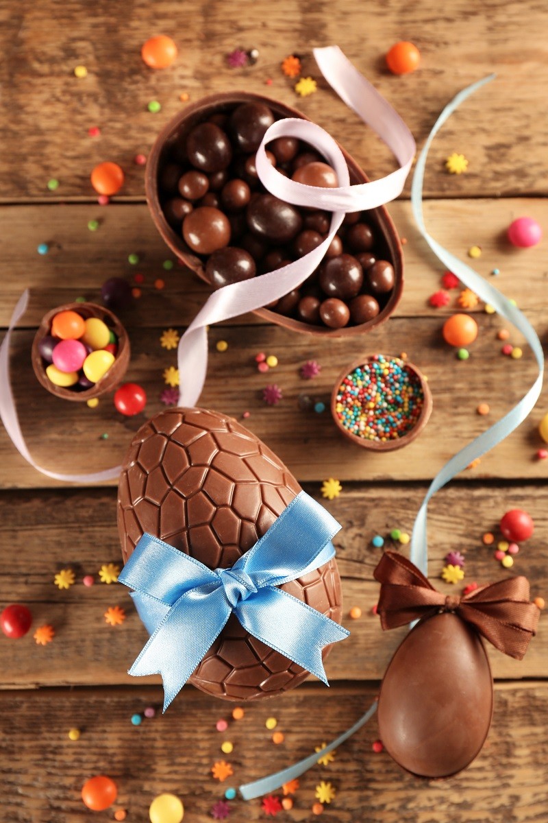 Chocolate Easter eggs with color ribbon bows on wooden background