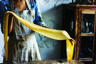 Young woman in a beautiful dress and an apron preparing the doug