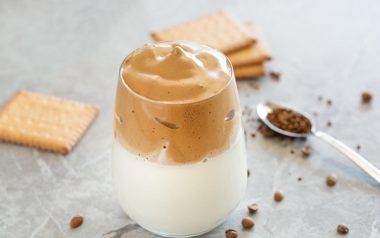Dalgona Coffee Cream with milk in glass cup with spoon in the background