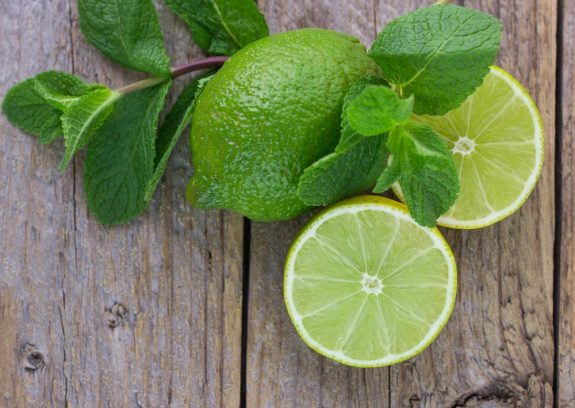 Juicy ripe limes and mint on wooden table