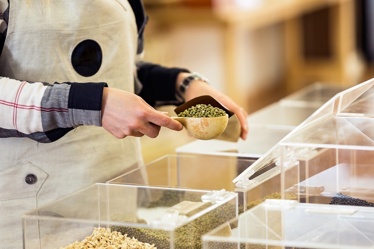 Saleswoman putting soya in a bulk shopping bag in an organic sto
