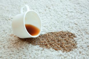 Cup of coffee spilled on white carpet, close up