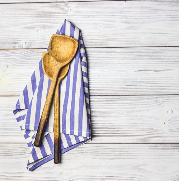 Cooking wooden utensils on white wooden background.