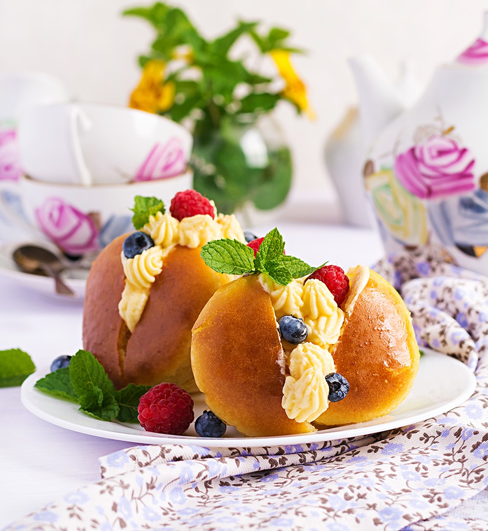 Rum baba decorated with whipped cream and fresh raspberry, blueb