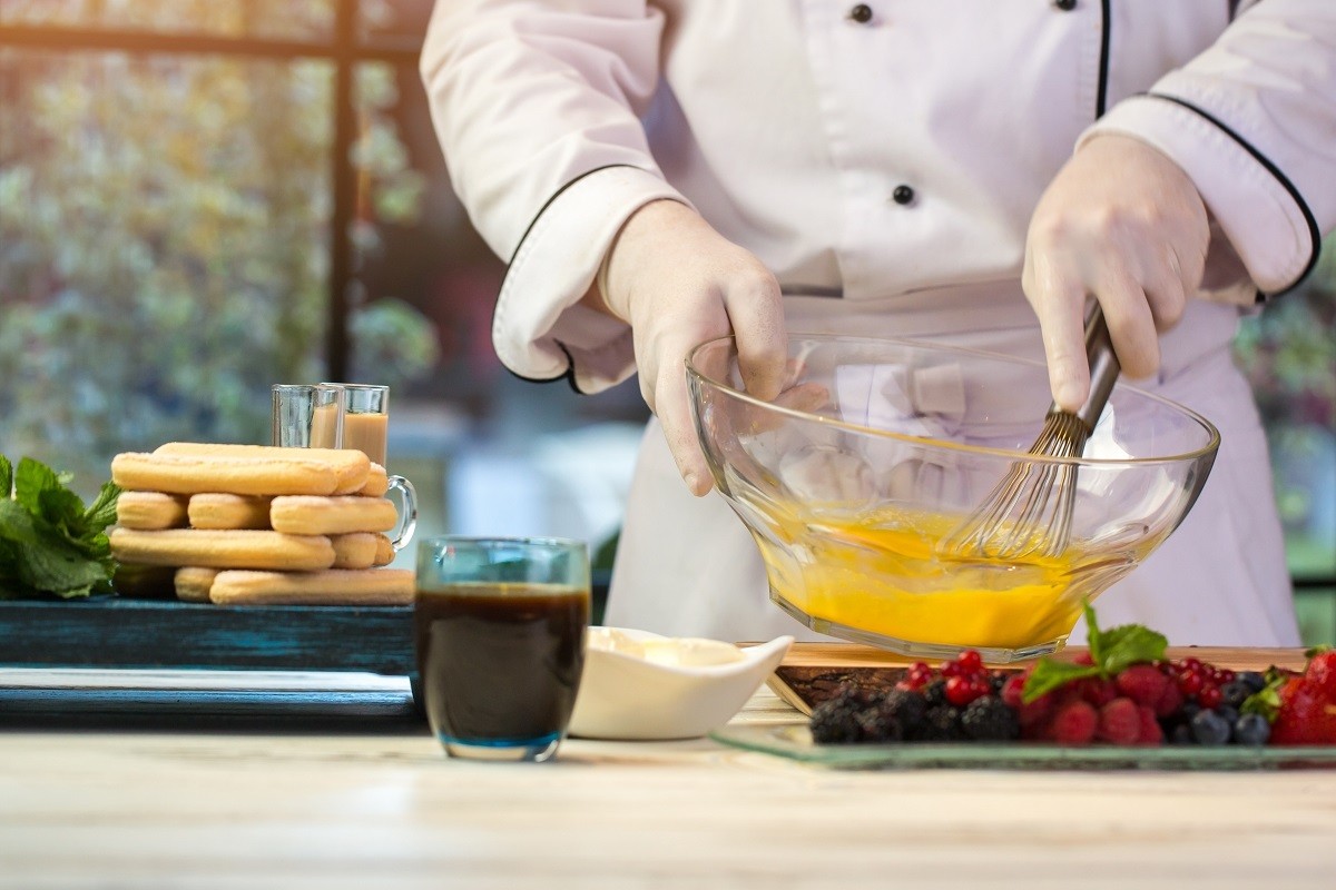 Hand,Whisks,Egg,In,Bowl.,Biscuits,And,Glass,With,Drink.