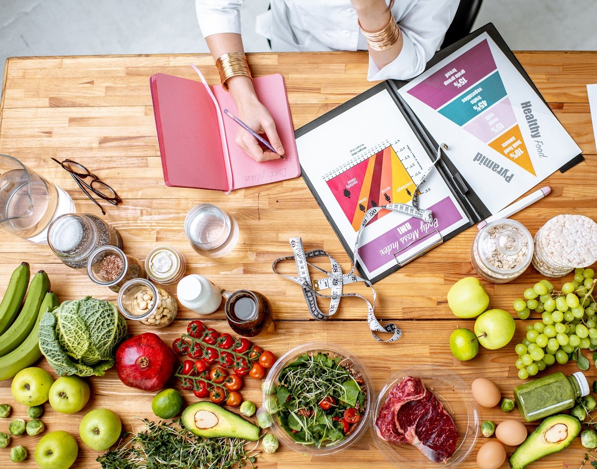 Writing a diet plan on the table full of healthy food