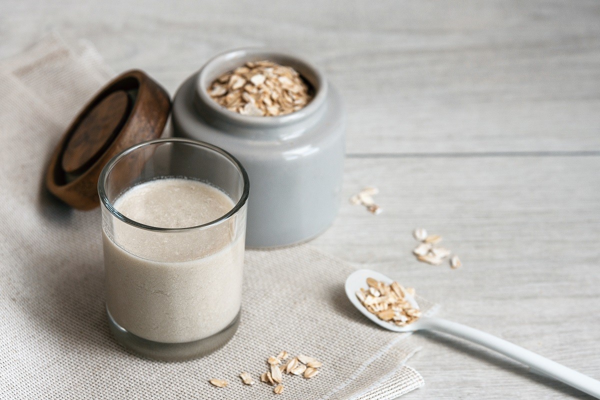 Vegan oat milk and ingredients on rustic fabric