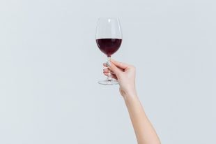 Female hand holding glass with wine
