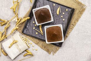 Miso paste, traditional Japanese seasoning. Two types, dark and light brown with dry soya beans. Sackcloth, bag, pods. Stone concrete background