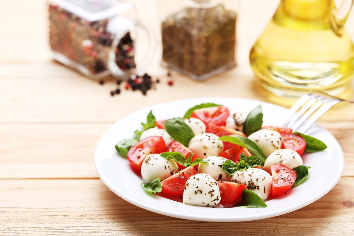 Mozzarella, tomatoes and basil leafs on brown wooden table