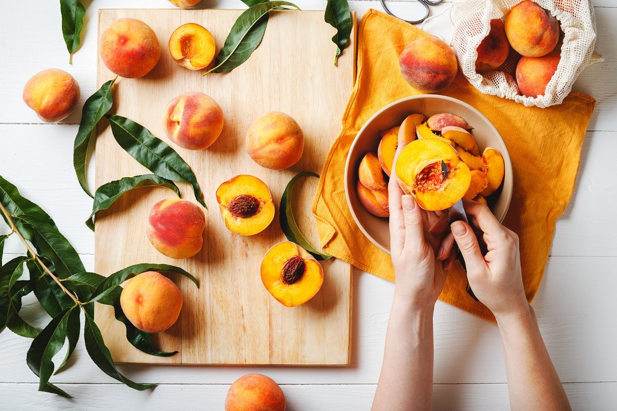 Woman cutting fresh sweet peaches. Top view.