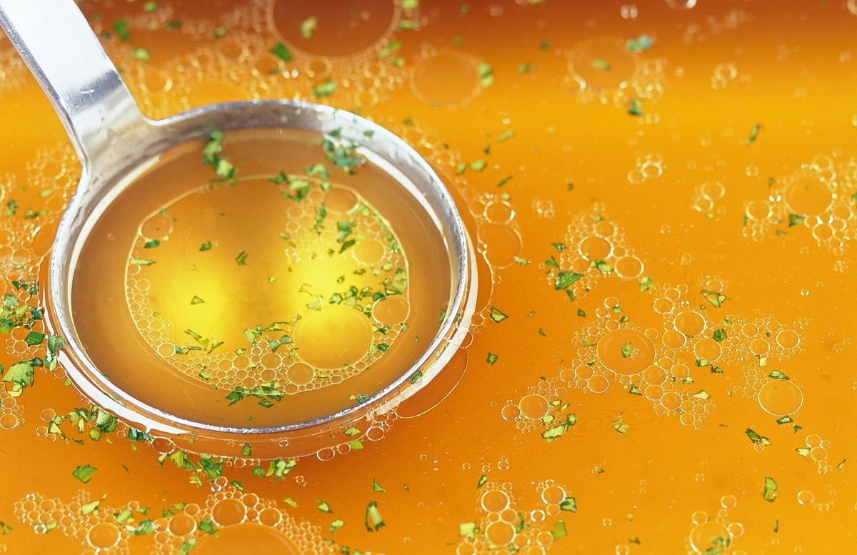 8287903 – bouillon with herbs and a metall spoon.