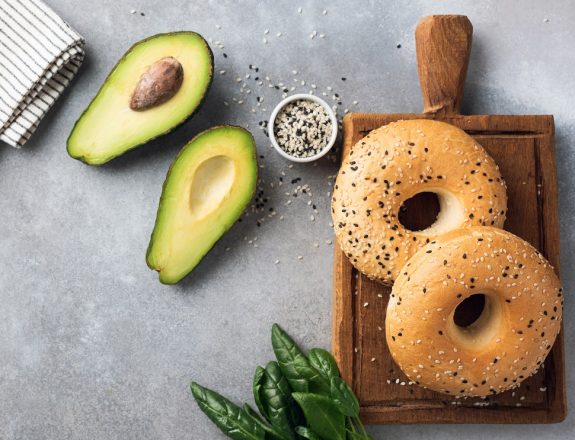 Halved avocado and bagels, healthy breakfast food ingredients