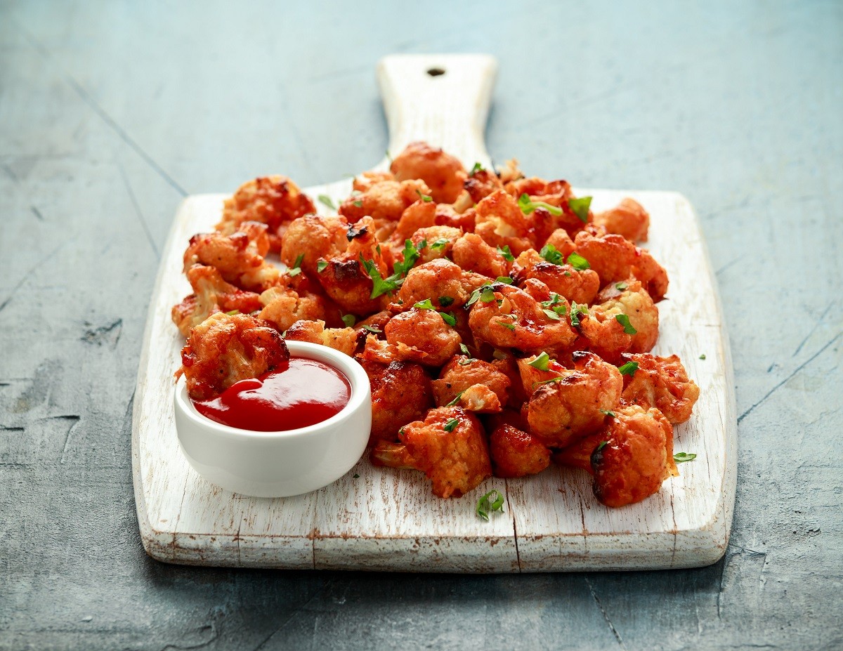 Vegan cauliflower buffalo wings on white wooden board