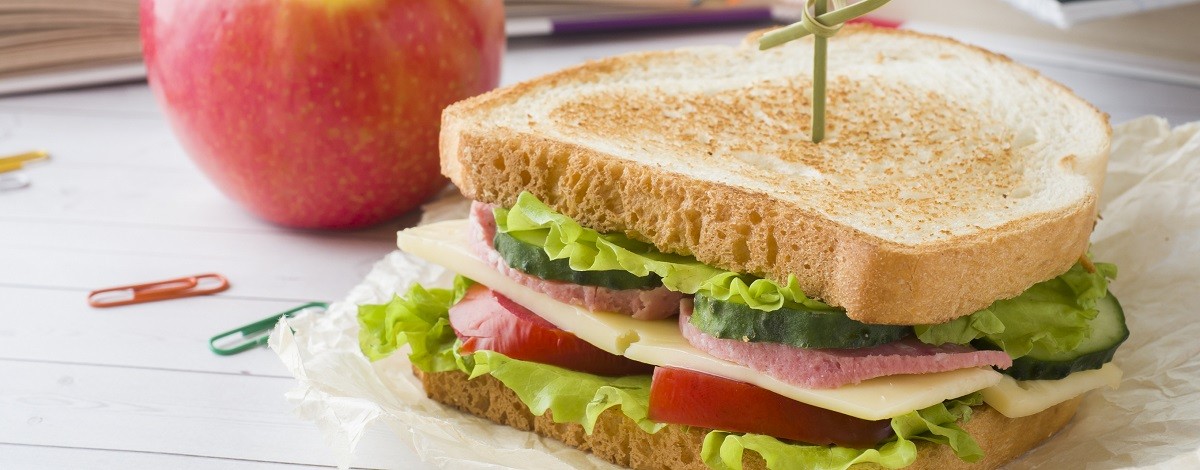 Snack for school with sandwich, fresh Apple and orange juice. Colorful school supplies.