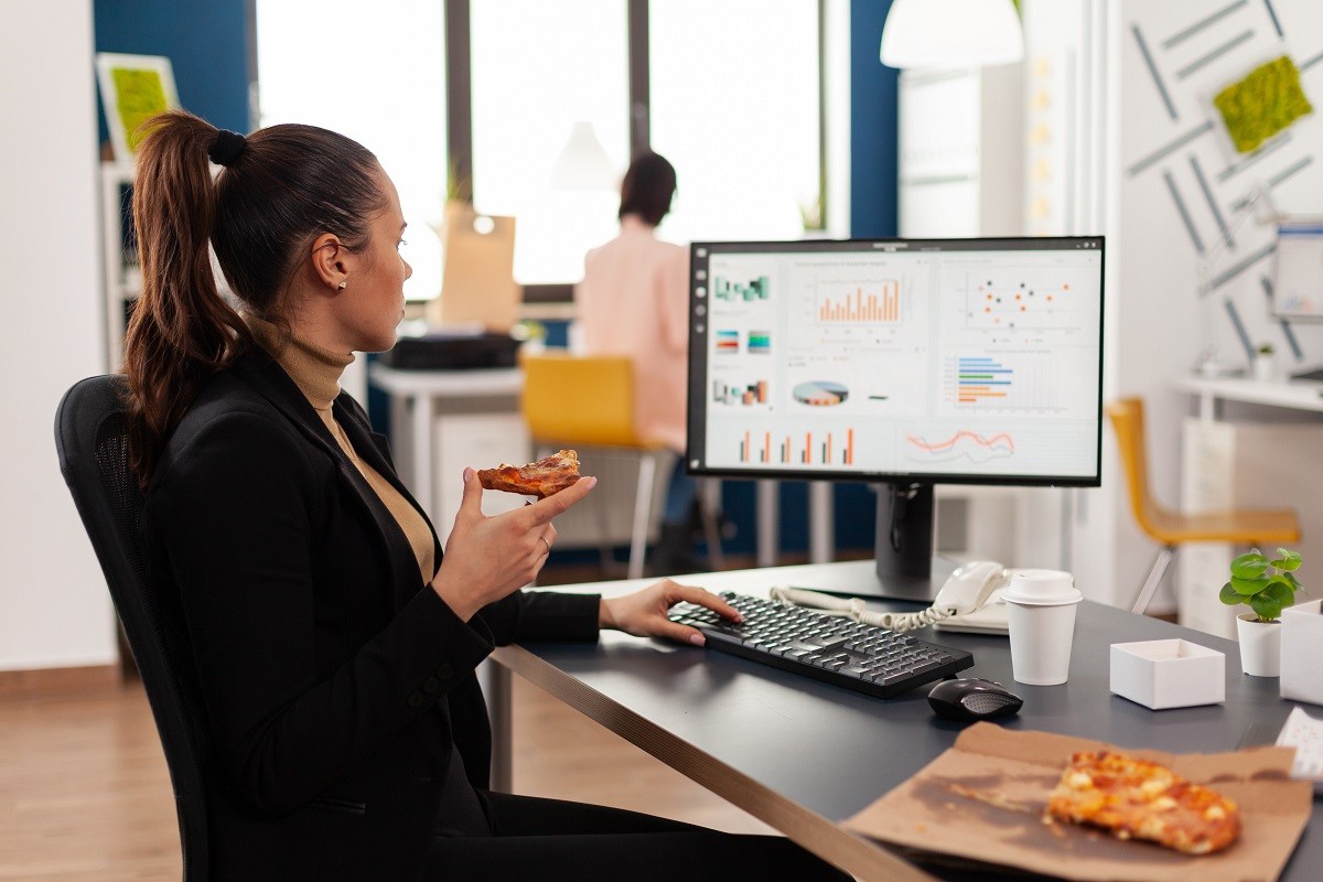Businesswoman having delivery food order on desk during takeout lunchtime working in business company