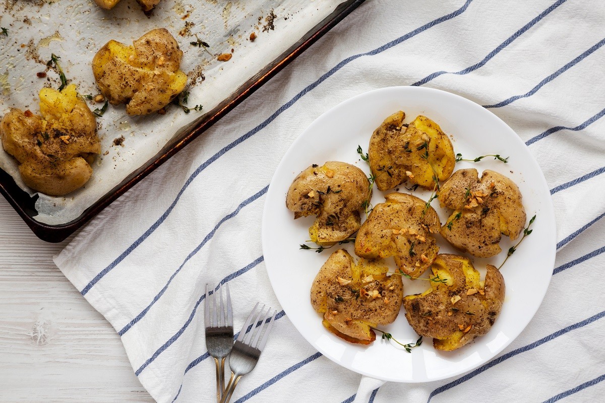 Homemade garlic thyme smashed potatoes on a white plate, top vie