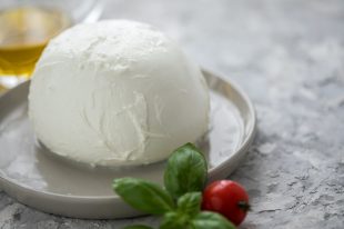 Buffalo mozzarella cheese ball with cocktail tomatoes, basil and olive oil on plate
