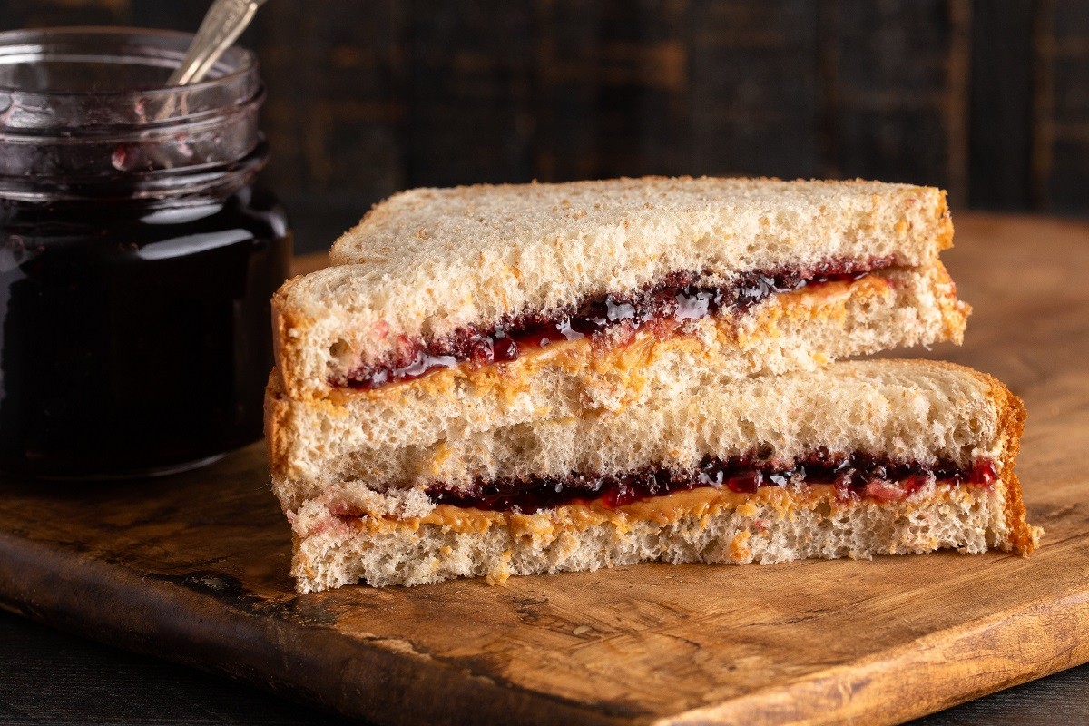 A Peanut Butter and Grape Jelly Sandwich on a Wooden Cutting Board