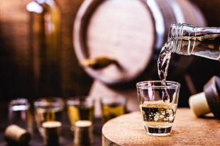 Glass of golden rum, with bottle. Bottle pouring alcohol into a small glass. Brazilian export type drink. Brazilian product for export, distilled drink known as brandy or pinga. Day of cachaça.