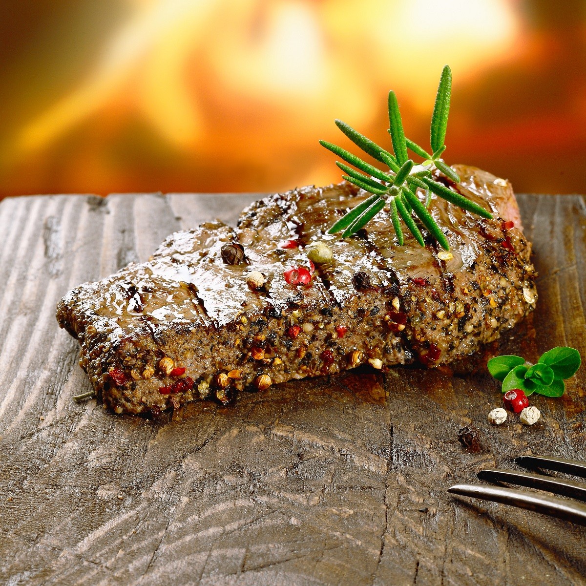 Rustic steak on wooden board in front of the fire