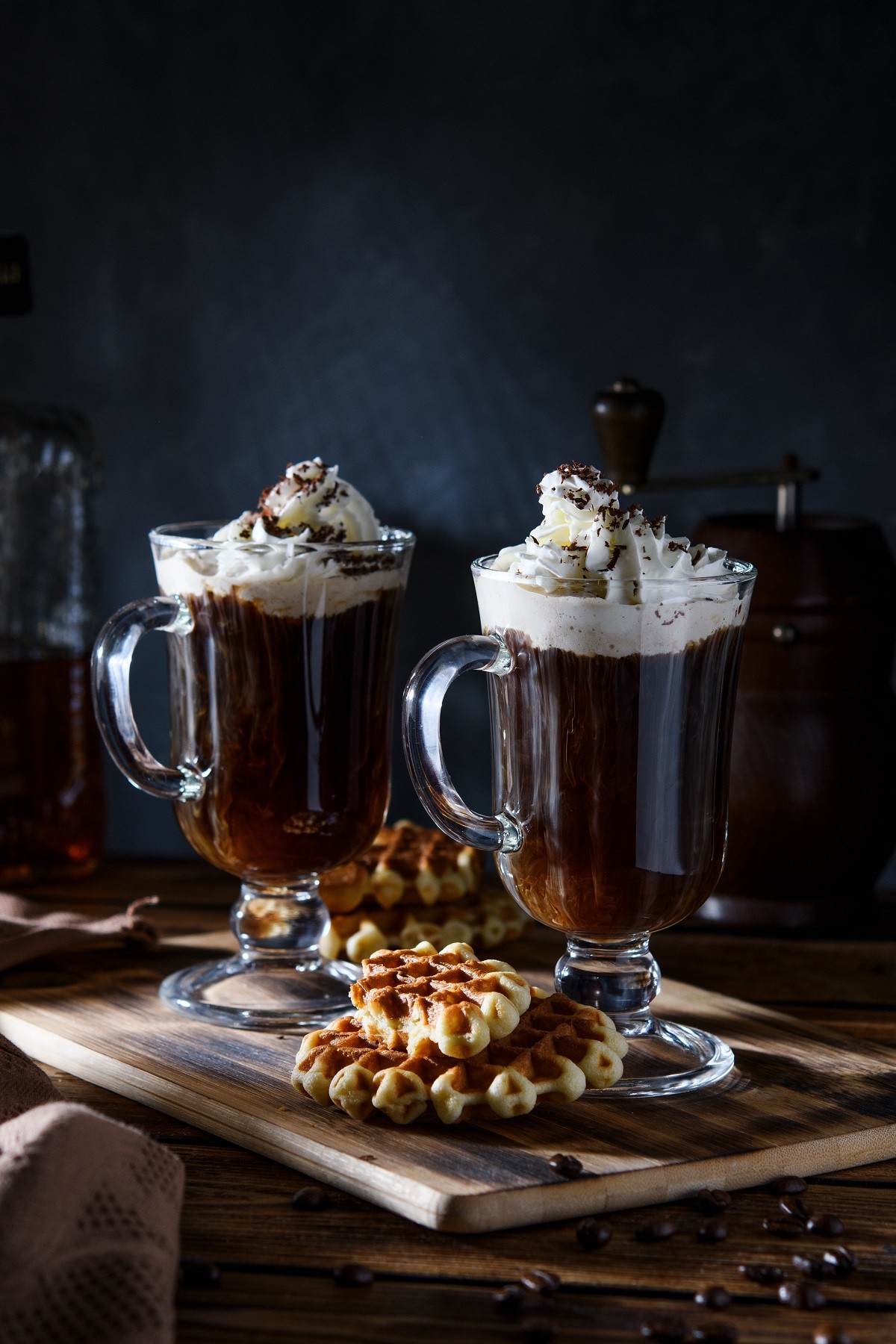 Two cups of coffee with whipped cream and grated chocolate on a dark concrete background. Viennese coffee with Viennese waffles.