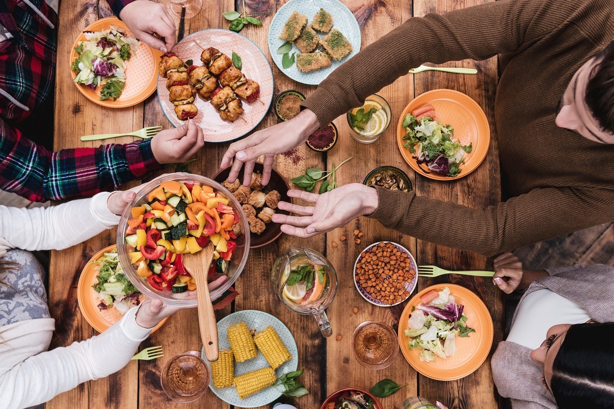 Friends having dinner. Top view of four people having dinner together while sitting at the rustic wooden table