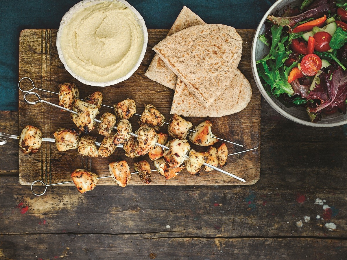 Greek chicken skewers with salad, hummus and pittas