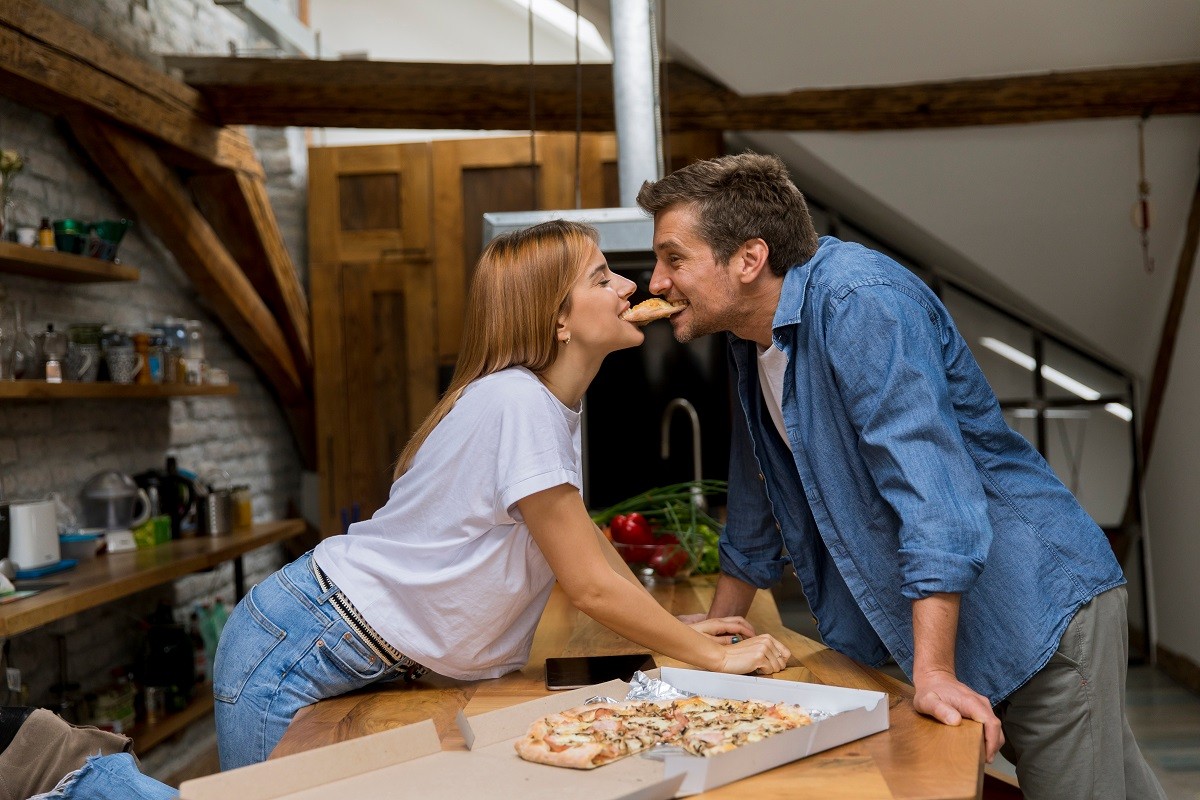 Young couple in love eating pizza in the rustic home