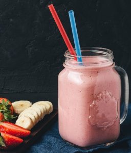 Smoothie with strawberry and banana in the jar at dark background