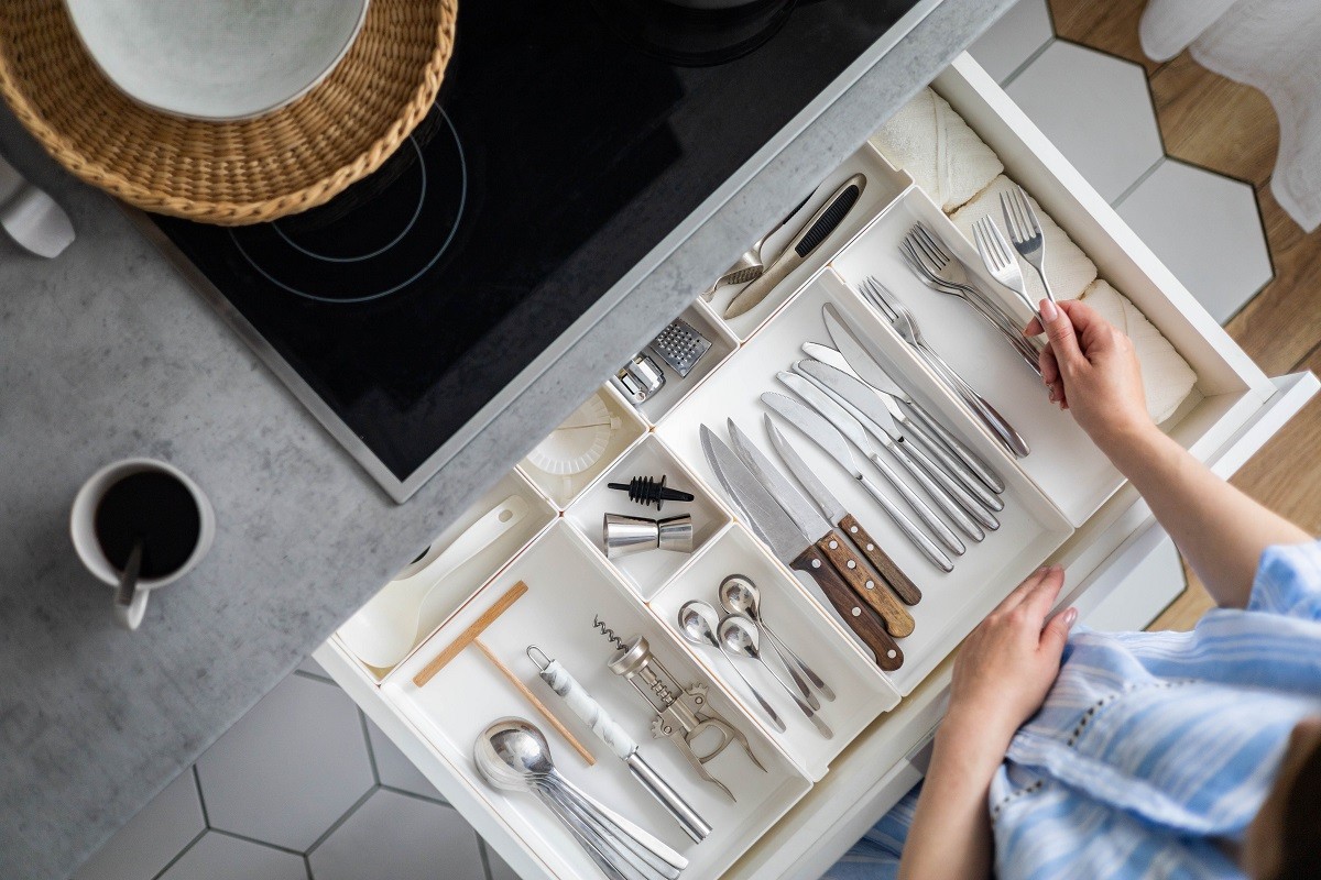 Top view closeup housewife hands tidying up cutlery in drawer general cleaning at kitchen