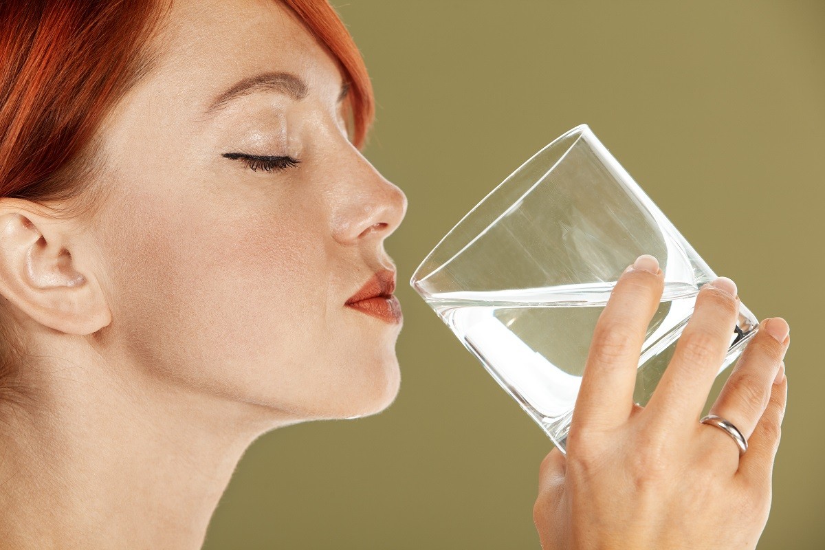 young red haired woman is drinking mineral water