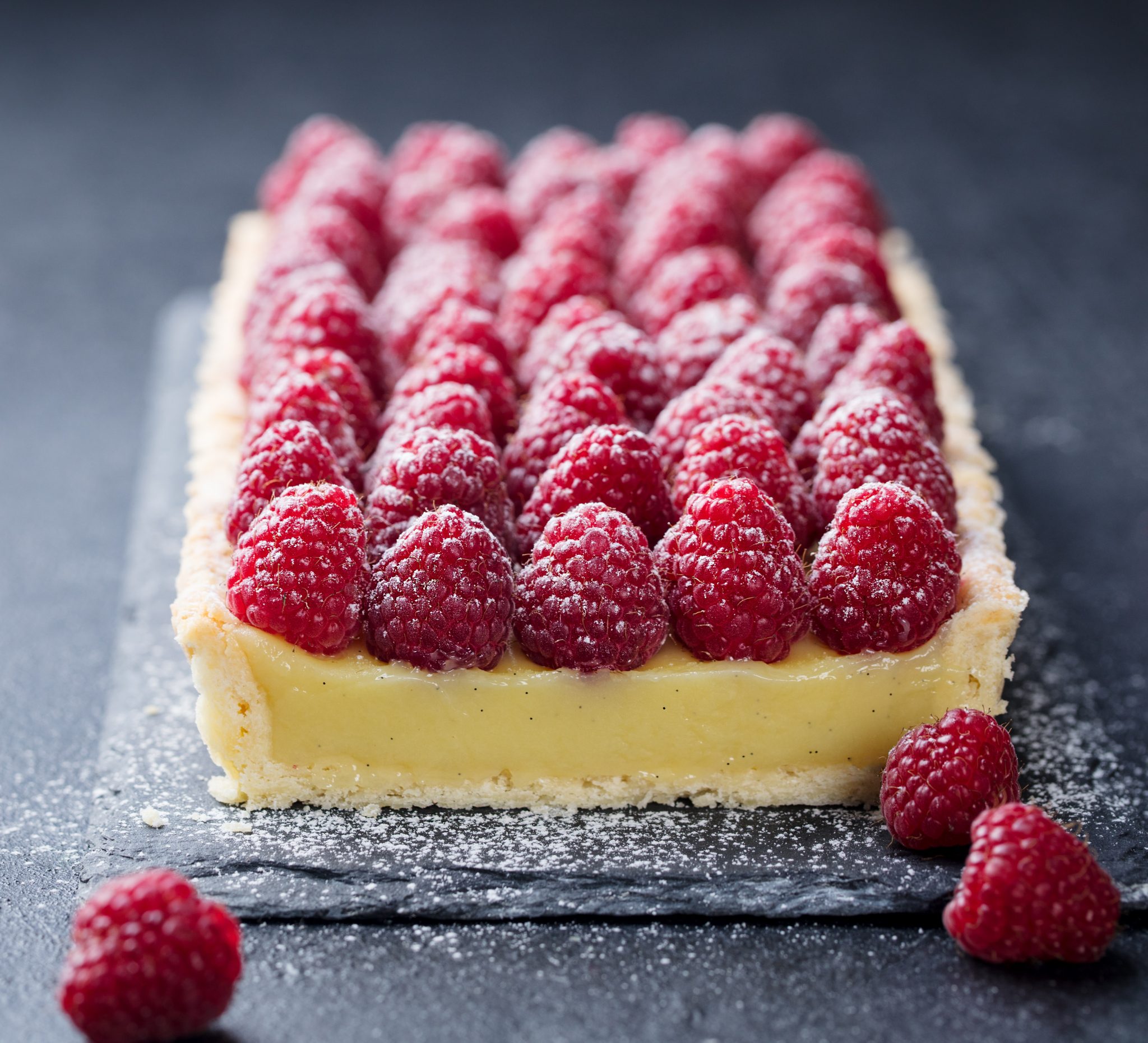 Raspberry,Tart,With,Vanilla,Custard,And,White,Chocolate,On,Slate