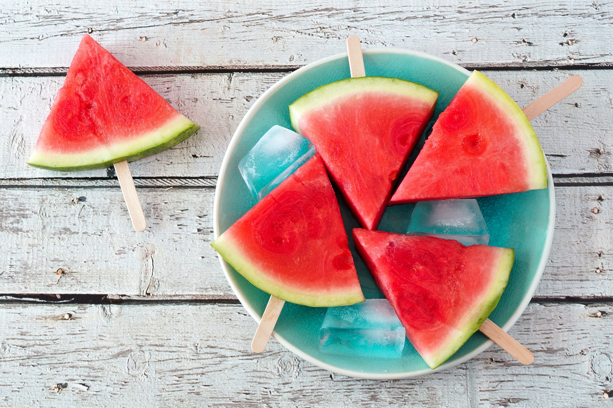 Watermelon slice popsicles on a vintage blue plate and rustic wood background